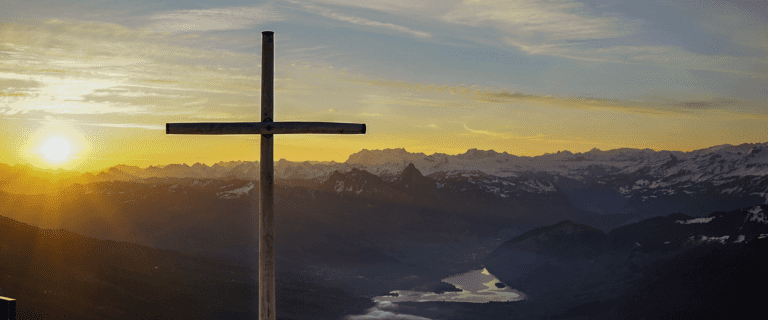 The sun shines behind a cross