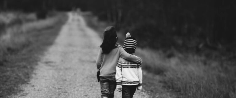 Two children walk down a path