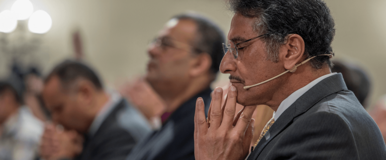 Image depicting Dr. Michael Youssef praying with members