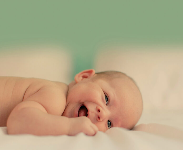 Infant lying on the bed happy and smiling
