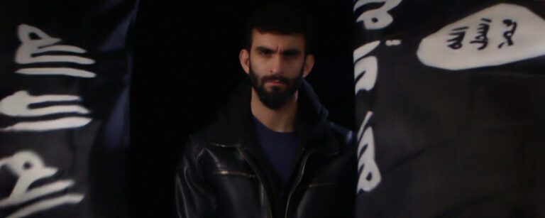 a young man looking into the camera and frowning with a blurry background
