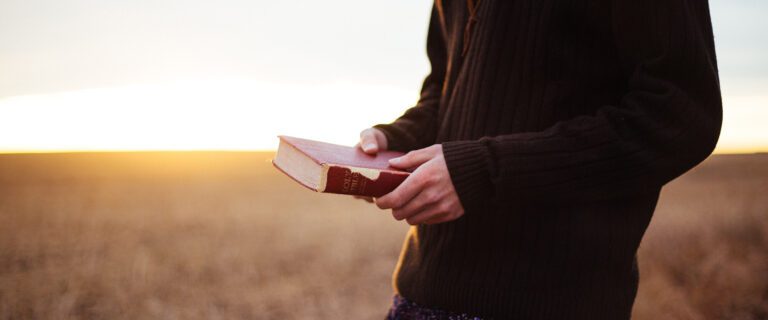 The torso of a man, holding a Bible