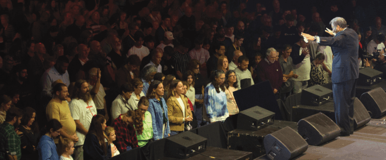 Dr. Youssef with open arms, praying with the congregation