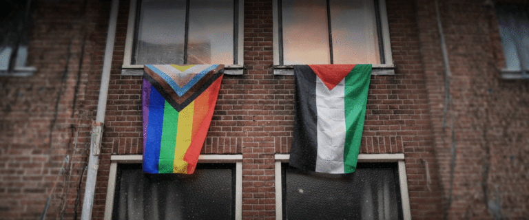 LGBTQ+ Pride flag and national flag of Palestine on the side of a building